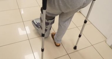 Hastane koridoru üzerinde koltuk değneğiyle yürüyen kadın 