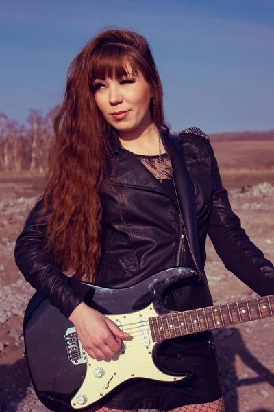 Девушка с гитарой в кожаной куртке — стоковое фото