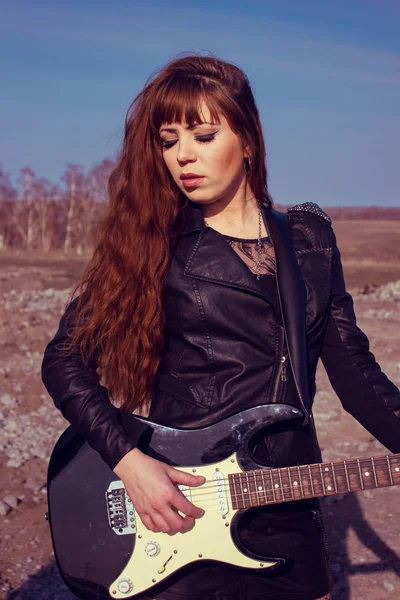 Девушка с гитарой в кожаной куртке — стоковое фото