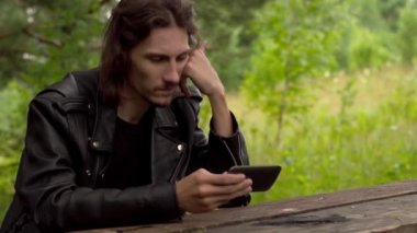 Adam telefonda ormanın içinde oturuyor