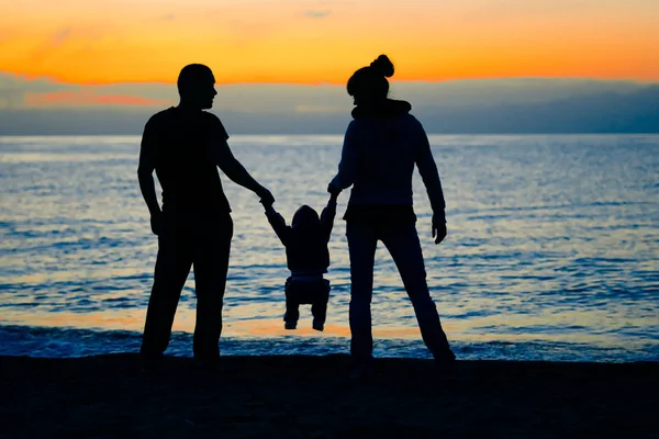 Семья на закате у моря — стоковое фото
