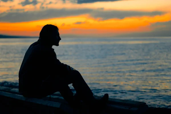 Gars debout au bord de la mer au coucher du soleil — Photo