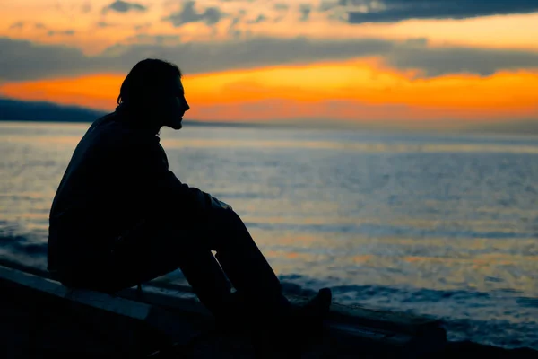Facet stoi przez morze o zachodzie słońca — Zdjęcie stockowe
