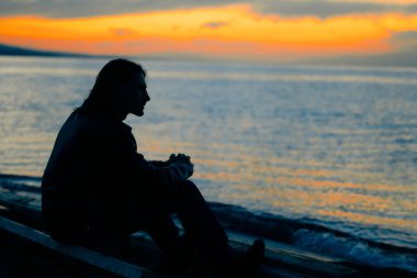 gün batımında deniz kenarında duran adam