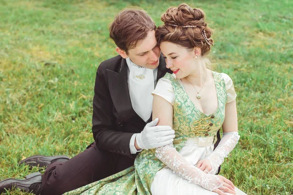 Пара в красивых костюмах сидит на траве — стоковое фото