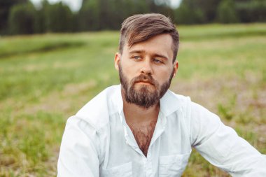 çimenlerin üzerinde oturan sakallı adam