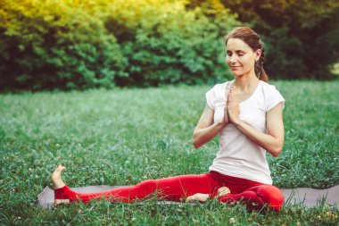 Kız çim üzerinde açık havada yoga yapıyor