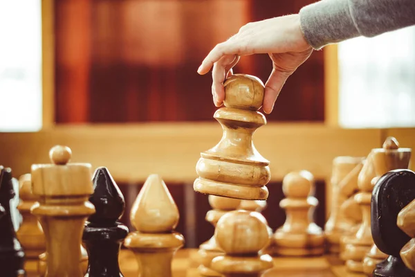 Mão segurando uma peça de xadrez sobre o tabuleiro — Fotografia de Stock