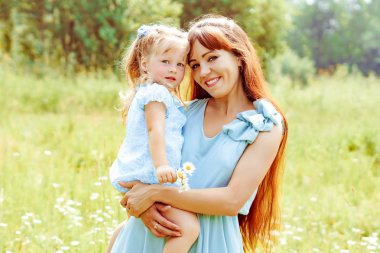 Anne kızını doğada kucaklıyor.