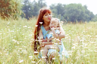 Anne kızını doğada kucaklıyor.