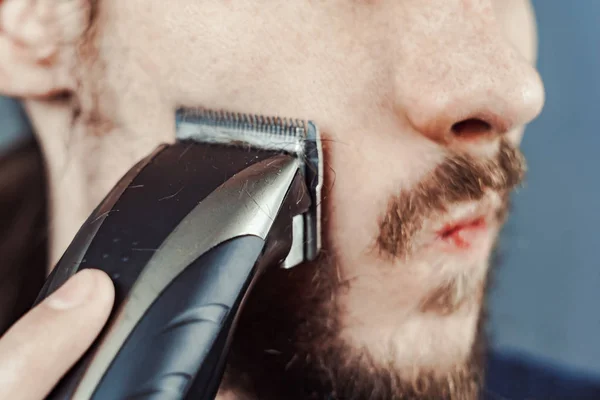男は電気かみそりで彼のひげを剃る — ストック写真
