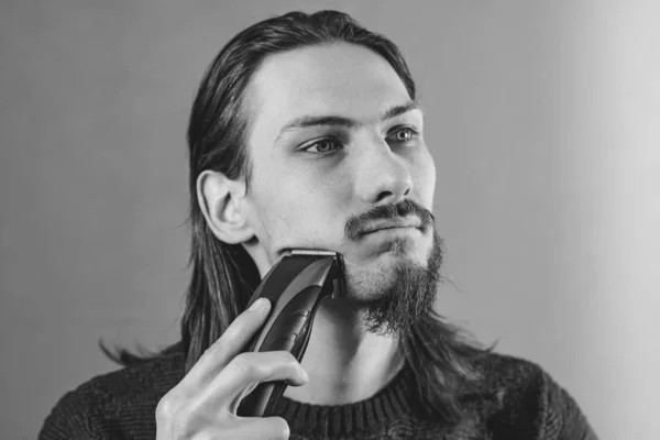 Guy scheert zijn baard met een elektrisch scheermesje — Stockfoto