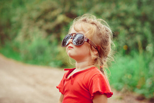 portrait of a little girl in sunglasses in nature