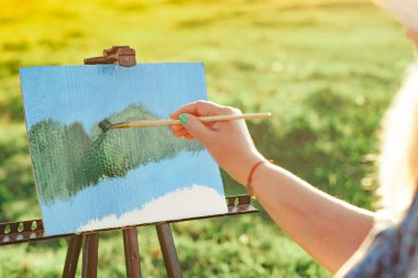 yaşlı bir kadın doğada bir resim boyar