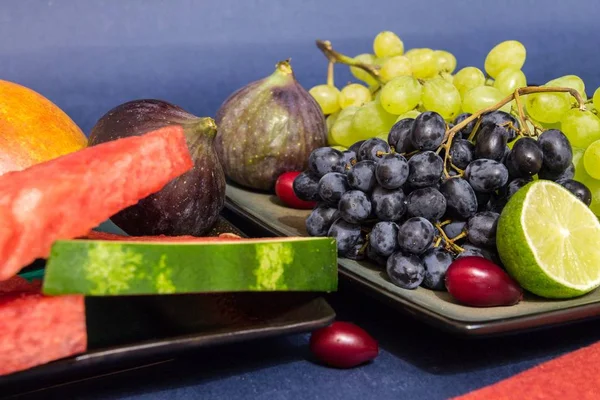 Frutas exóticas variedad bodegón con uvas, higos, lima, melocotón, mango y sandía — Foto de Stock