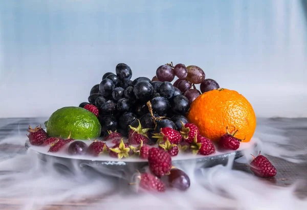 Deliciosa ensalada de frutas en plato sobre mesa, lima, frambuesa, uvas — Foto de Stock