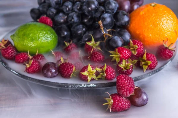 Delicious fruits salad in plate on table, lime, raspberry, grapes — Stock Photo, Image
