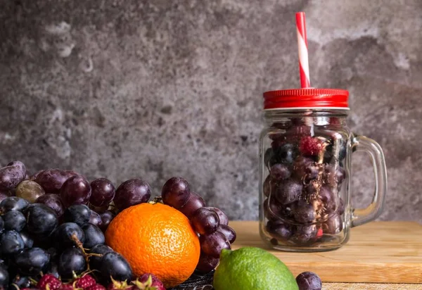 Frutas en forma de tarro de batido. Uvas, frambuesa, lima, fondo oscuro — Foto de Stock