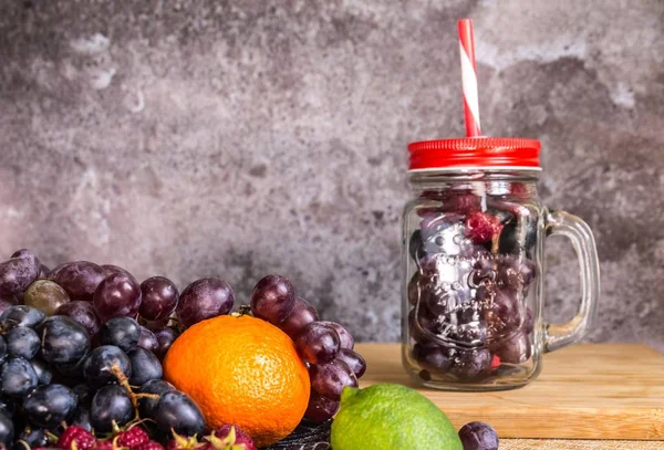 Turmix üveg alakú gyümölcsök. Szőlő, málna, lime, sötét háttér — Stock Fotó