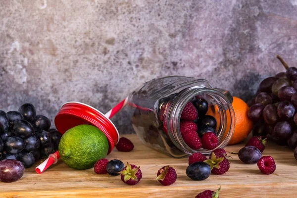 Turmix üveg alakú gyümölcsök. Szőlő, málna, lime, sötét háttér — Stock Fotó