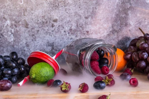 スムージー瓶形の果物。ブドウ、ラズベリー、ライム、暗い背景 — ストック写真