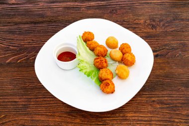 Peynir topları beyaz tabakta marul yaprakları ve sos ile