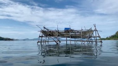 Kazık arazileri, denizdeki geleneksel balık tuzakları ahşaptan yapılmış mavi gökyüzü arka planına karşı.