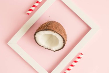 Pastel pembe arka plan en az yaratıcı kavramı karşı Hindistan cevizi yarım içinde beyaz çerçeve.