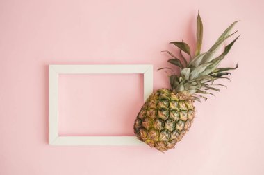 Ananas ve boş resim çerçevesini pastel pembe arka plan en az yaratıcı kavramı karşı düz yatıyordu.