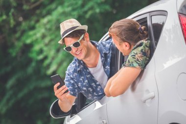 İki hipster adam akıllı telefon kullanarak araç pencereleri dışarı. Yol konsepti yaz tatil seyahat.