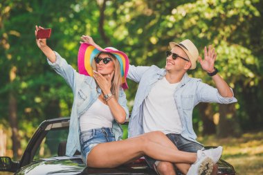 Doğada kendi Cabrio araba arkasında otururken alarak selfie genç çift.