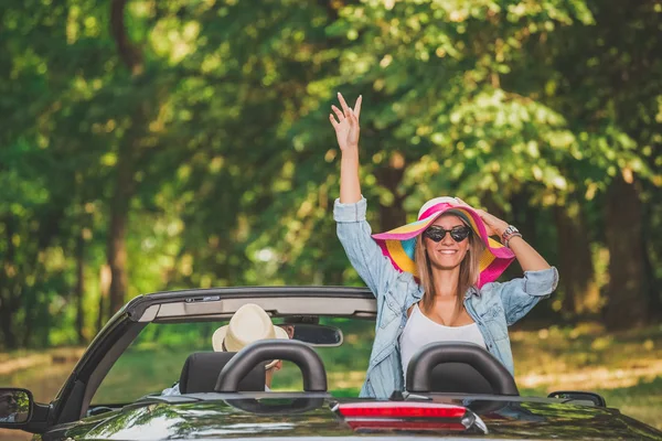 Mutlu genç moda kadın yükseltilmiş kol Cabrio araba sevgilisi ile seyahat ile.