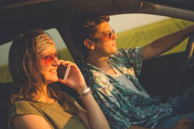 Güzel çift sürüş ve smartphone kullanarak arabada. Seyahat ve teknoloji kavramları.