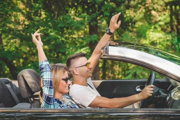 Beautiful couple going on vacation by driving in cabriolet car in nature.