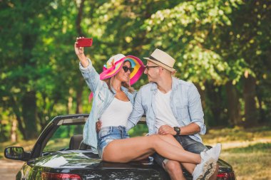 Doğada kendi Cabrio araba arkasında otururken alarak selfie genç çift.