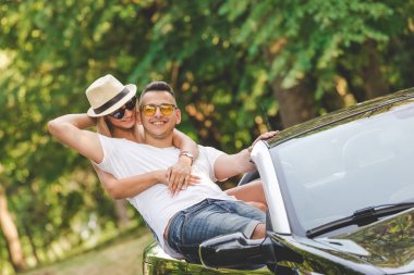 Genç moda çift doğada cabriolet arabada. Yol çelme takmak yaz tatil konsepti üzerinde.