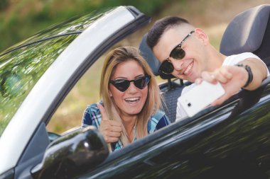 Güzel çift doğa cabriolet arabalarında kendi kendine portre alarak.