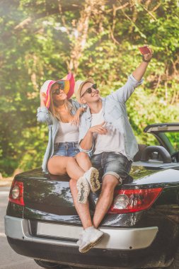 Cabriolet gövde üzerinde oturan ve kendi kendine portre çekici şık çift. Yol konsepti yaz tatili.
