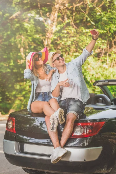 Modisches Paar Das Auf Dem Kofferraum Des Cabrios Sitzt Und — Stockfoto