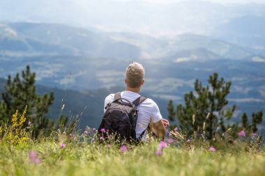 Bir tepe üzerinde oturan ve manzarayı adam.