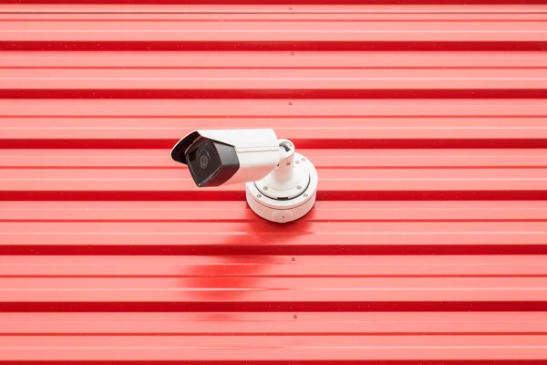 Security camera on red wall minimal creative concept.