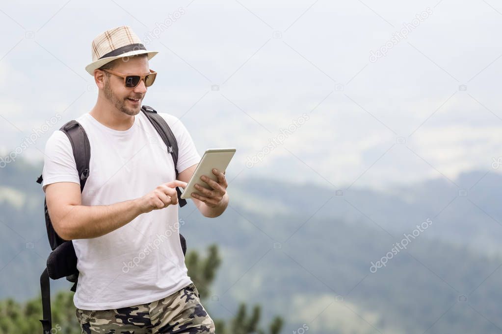 Young tourist using digital tablet in nature.