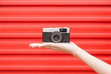 Retro fotoğraf makinesi kırmızı arka planda tutan el yakın çekim