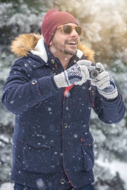 Vintage fotoğraf makinesi doğada holding neşeli adam. Kış sahne arka plan.