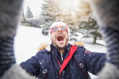 Adam santa şapka ve güneş gözlüğü selfie karlı gününde alarak.