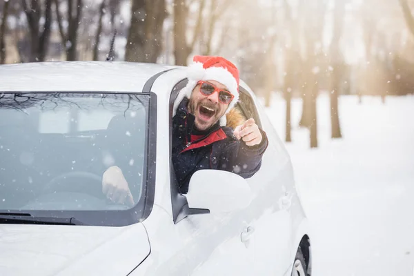 Araç sürücüsü ile Noel Baba şapkası araba penceresinden portresi. Yol kış tatil ve tatil konsepti üzerinde.