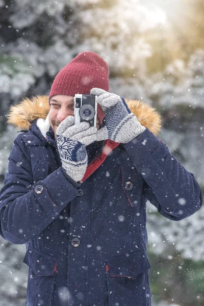 Doğada vintage fotoğraf makinesi kullanan genç adam. Kış sahne arka plan.