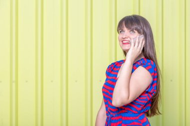 Sarı arka plana karşı cep telefonu kullanan güzel kadın portresi. Kopya için alan.