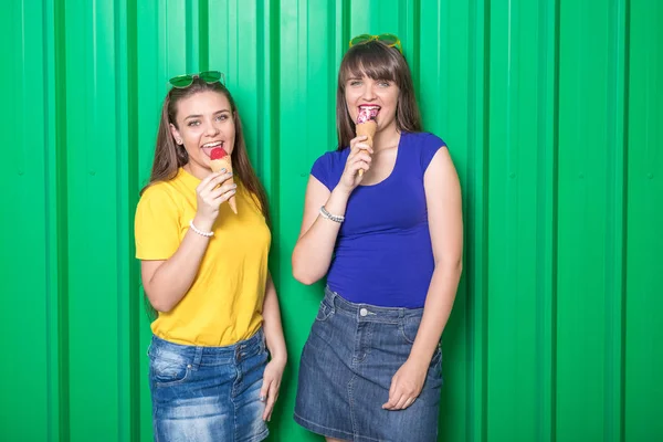 Dos Hermosas Chicas Jóvenes Comiendo Helado Sobre Fondo Verde Concepto — Foto de Stock