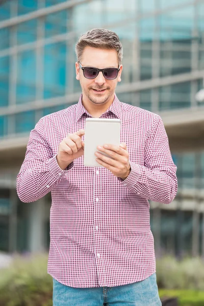 Handsome executive holding and looking at digital tablet device outdoors.